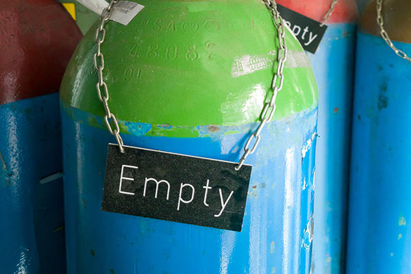 a close up of a cylinder gas container with a sign that reads "empty" on it