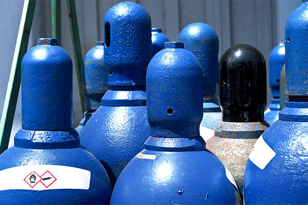 close ups of the tops of blue cylinder gas containers outside
