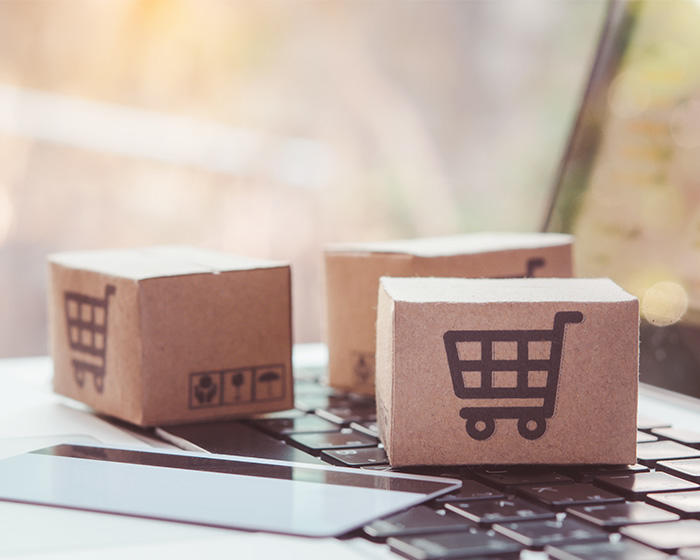 tiny boxes with shopping carts and an unmarked credit card on top of a Mac laptop